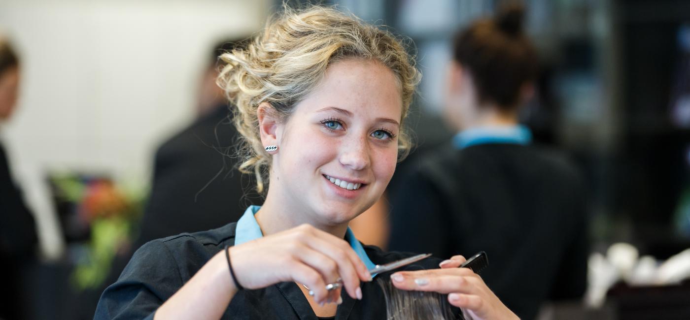 Studente haarverzorging knipt het haar van een klant
