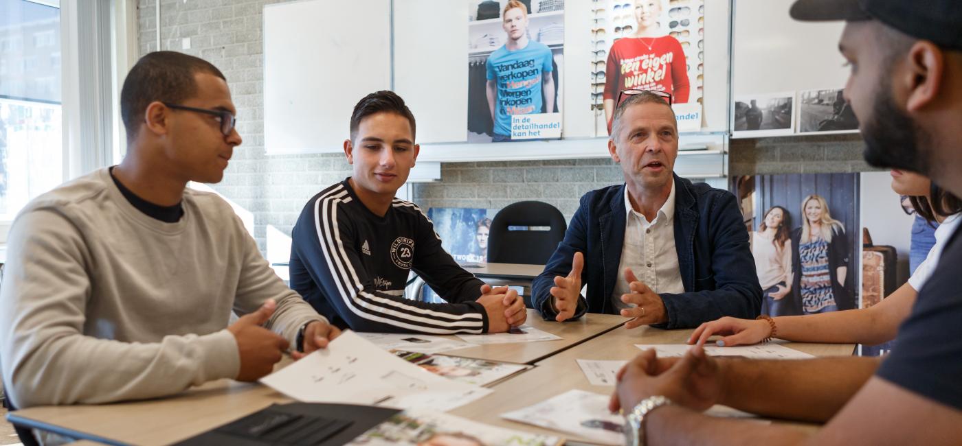 Docent met studenten aan tafel