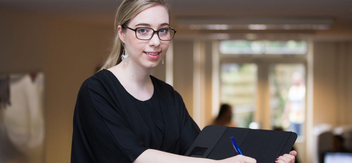 Meisje kijkt naar camera met hand op schrijfblok