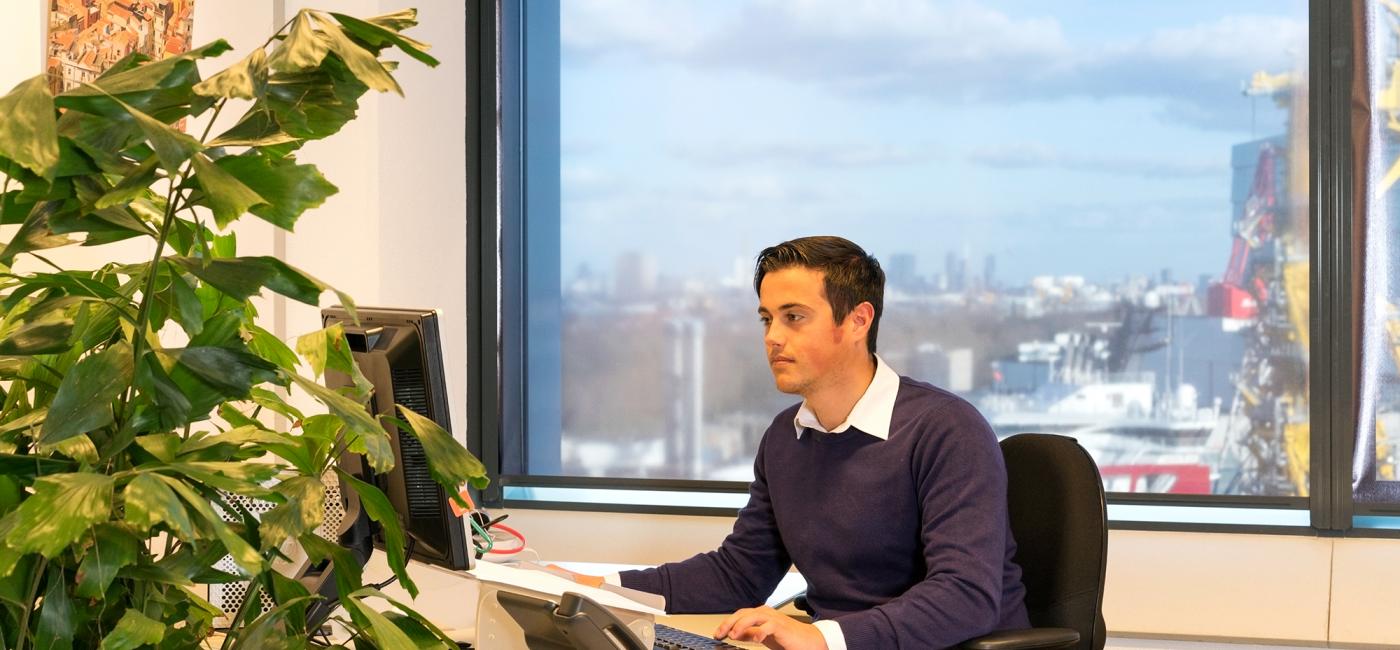 Jonge man zit aan bureau te werken