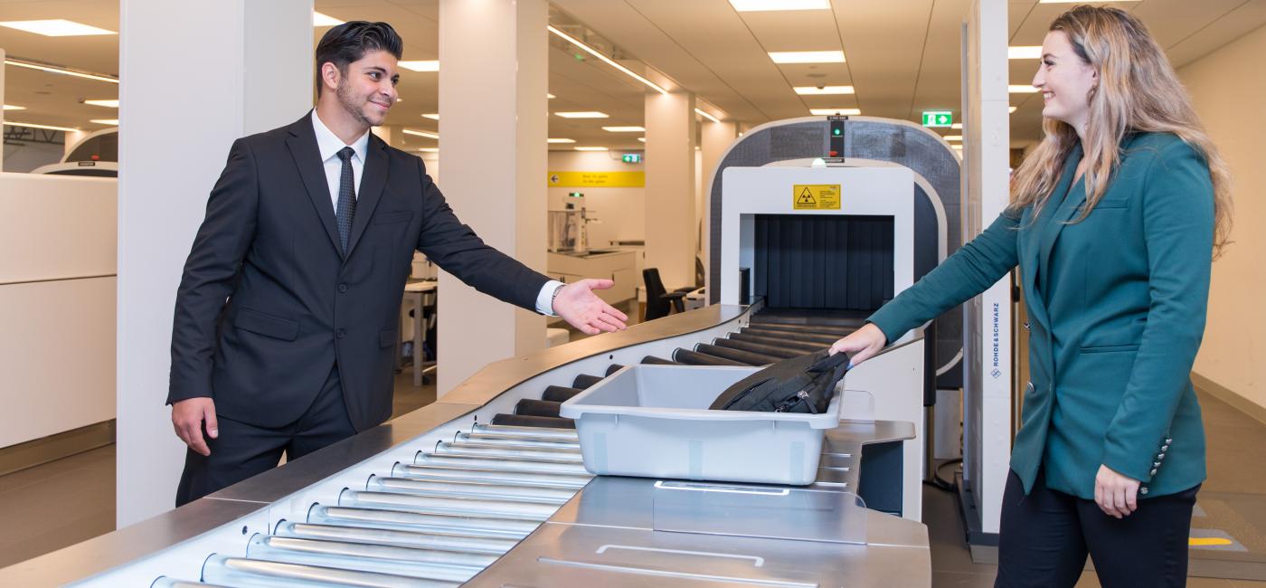 Jonge luchthaven beveiliger met jonge vrouw, bij controle punt