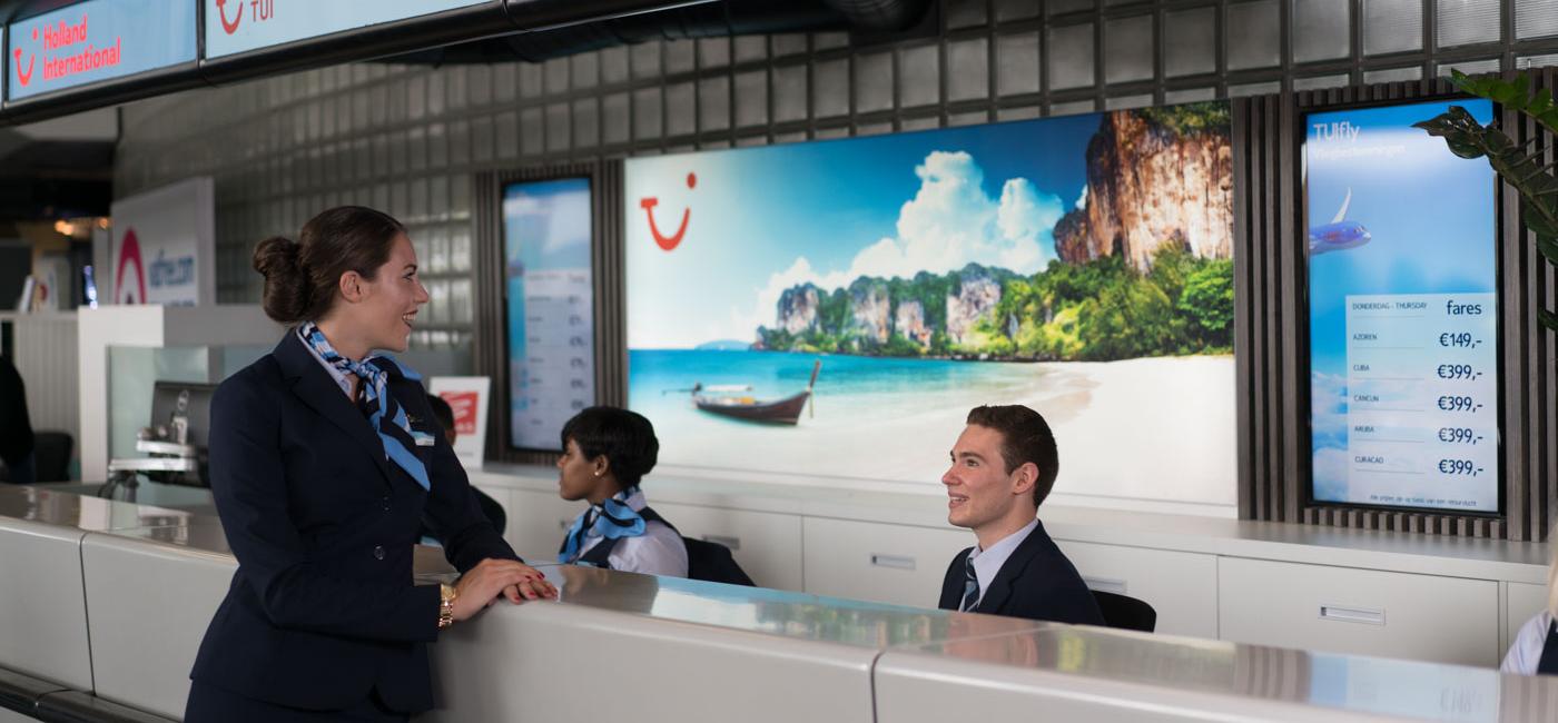 Jonge stewardess staat aan balie