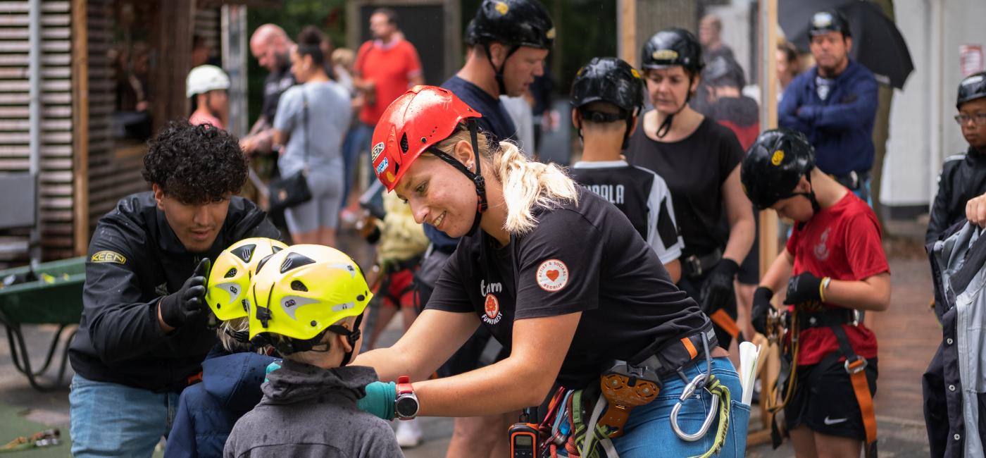 Jonge man en vrouw helpen kinderen met klimoufit