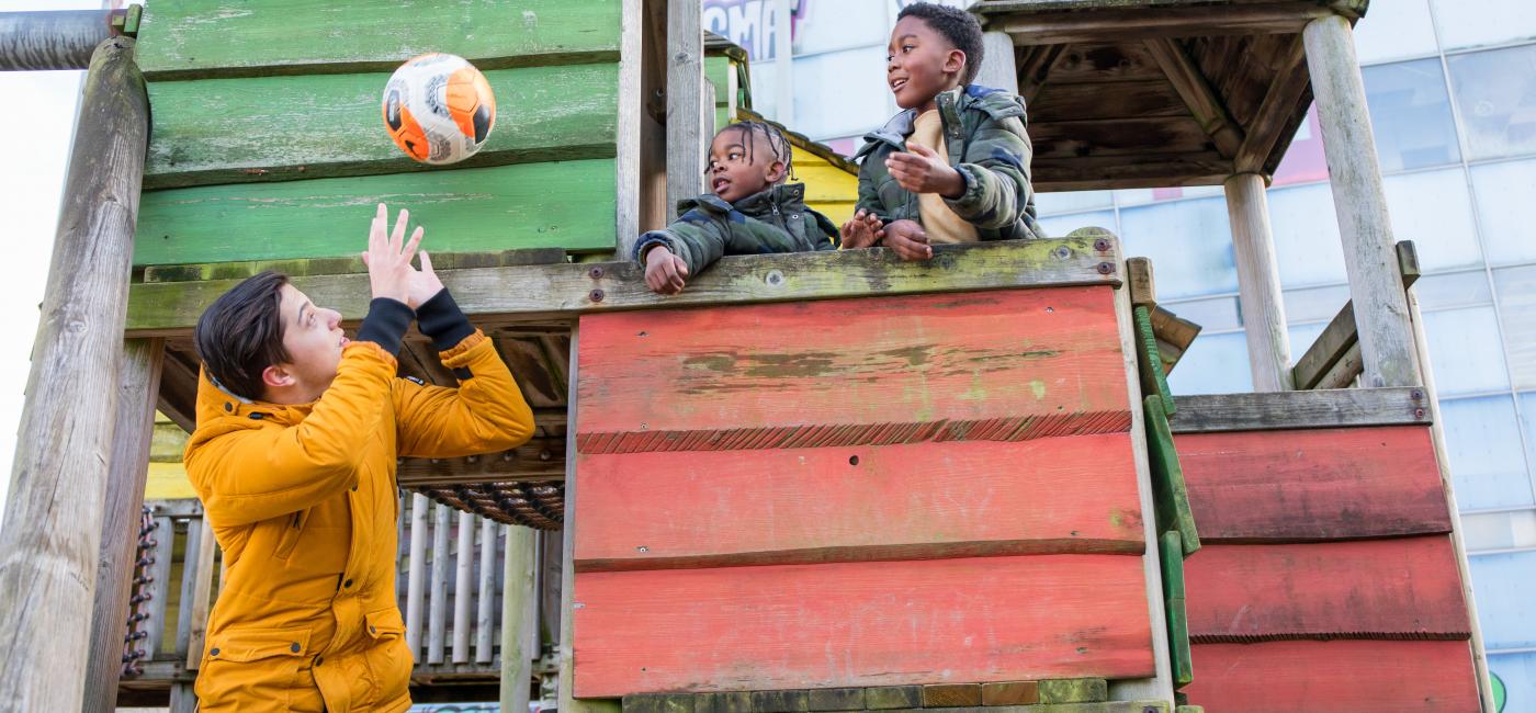 Jonge man speelt in speeltuin met kinderen