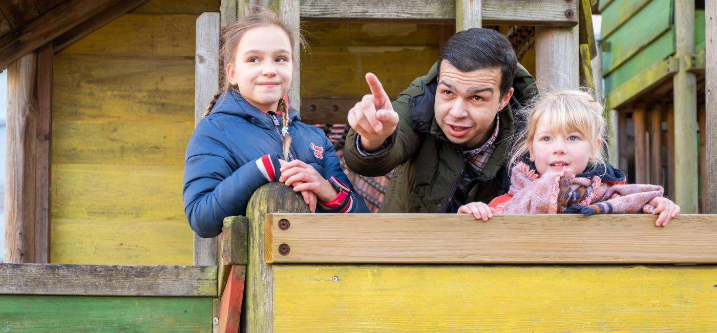 Jonge man met twee kinderen op speeltoestel