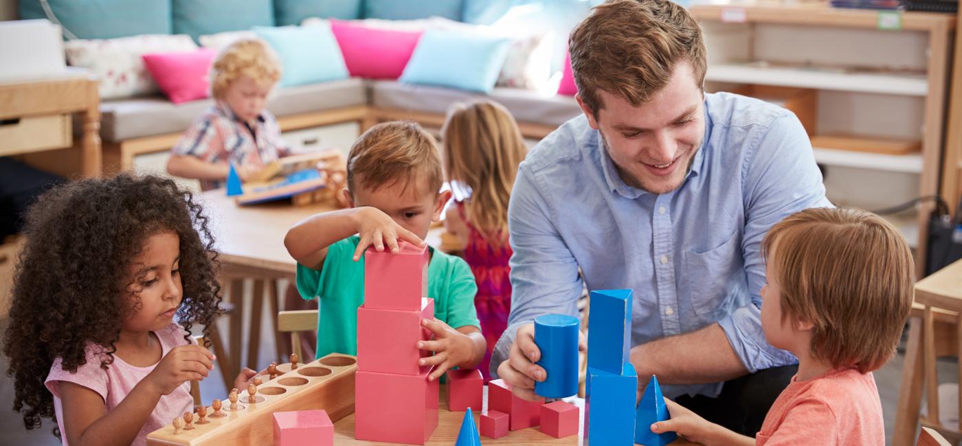 Jongeman speelt aan tafel met kinderen met blokken