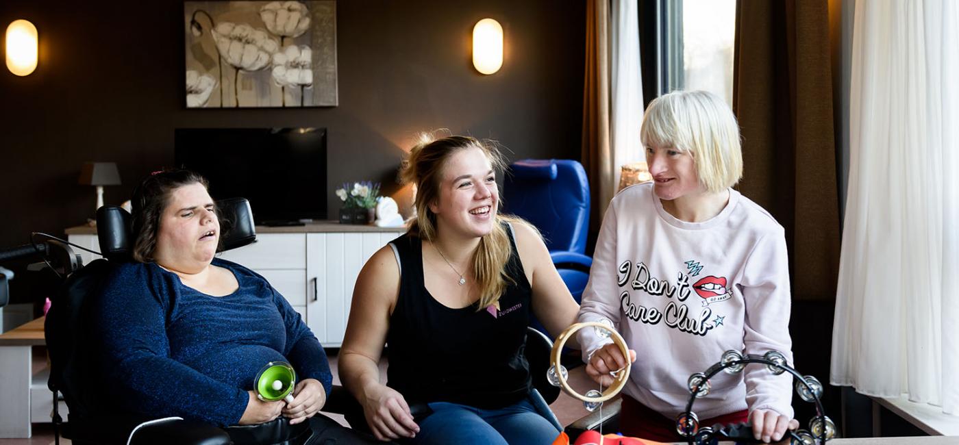 Gehandicapte mensen maken muziek met een vrouwelijke begeleider