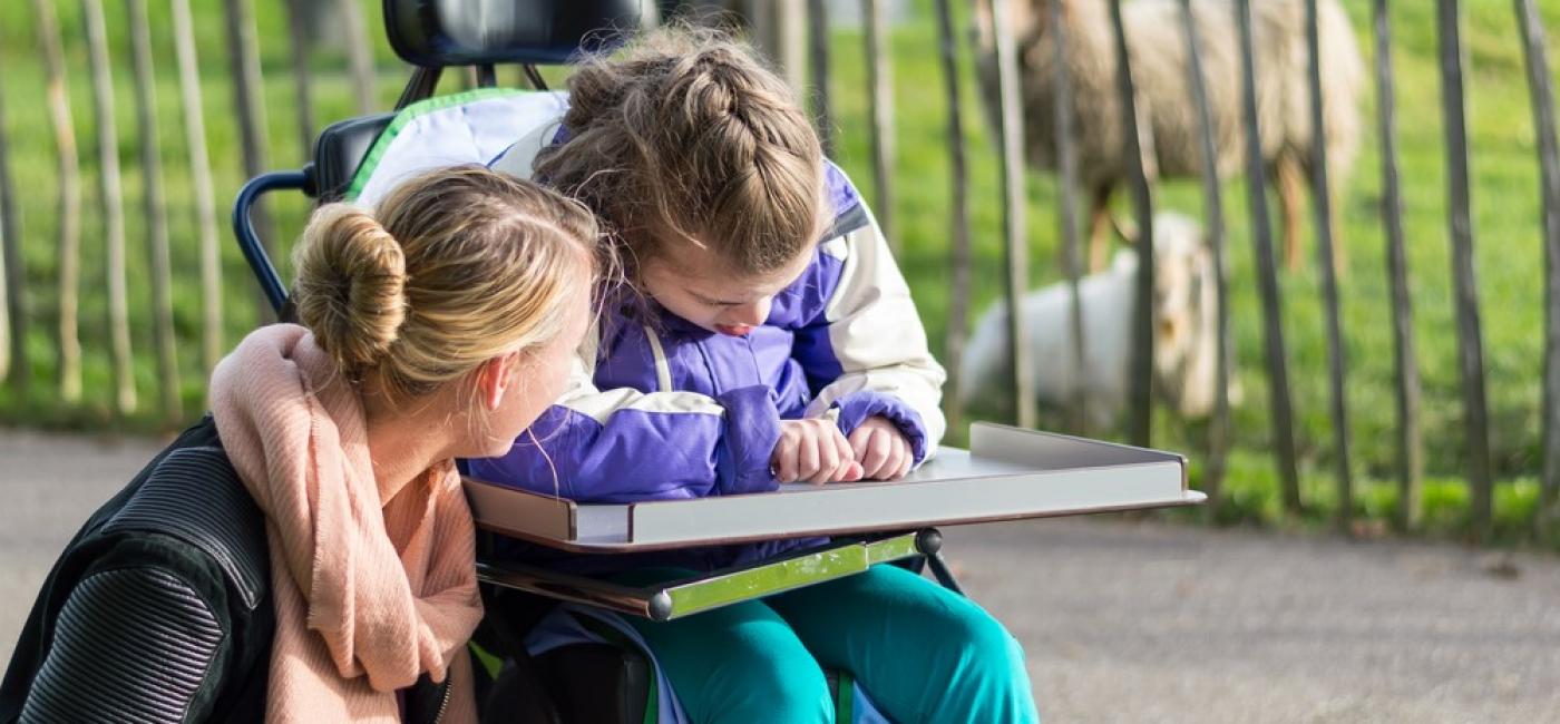 Vrouw praat met gehandicapt meisje in rolstoel 