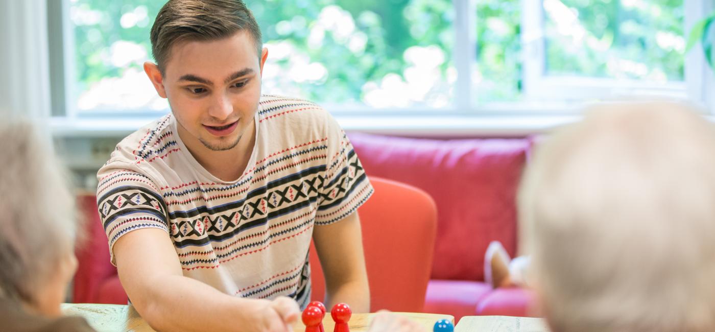 Jonge man doet spelletje met ouderen