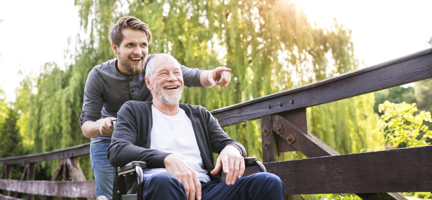 Buiten wandelen met oudere man in rolstoel